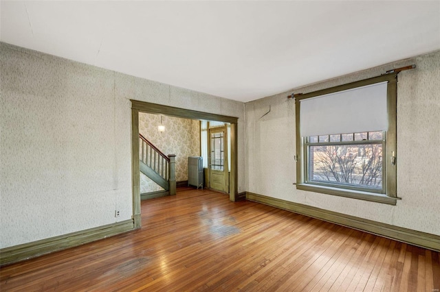 empty room featuring hardwood / wood-style flooring and radiator heating unit