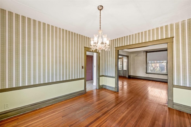 unfurnished room featuring wood-type flooring, a baseboard heating unit, and a chandelier