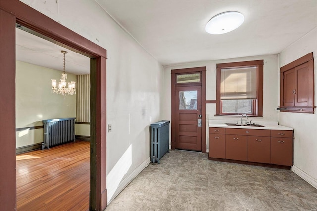 kitchen featuring sink, radiator, a notable chandelier, light hardwood / wood-style floors, and decorative light fixtures