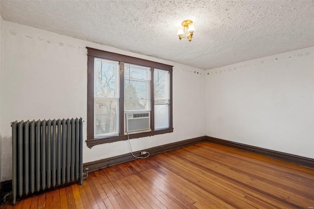 unfurnished room with cooling unit, radiator, hardwood / wood-style flooring, and a textured ceiling