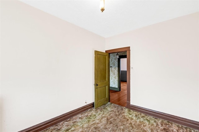 carpeted spare room featuring radiator heating unit