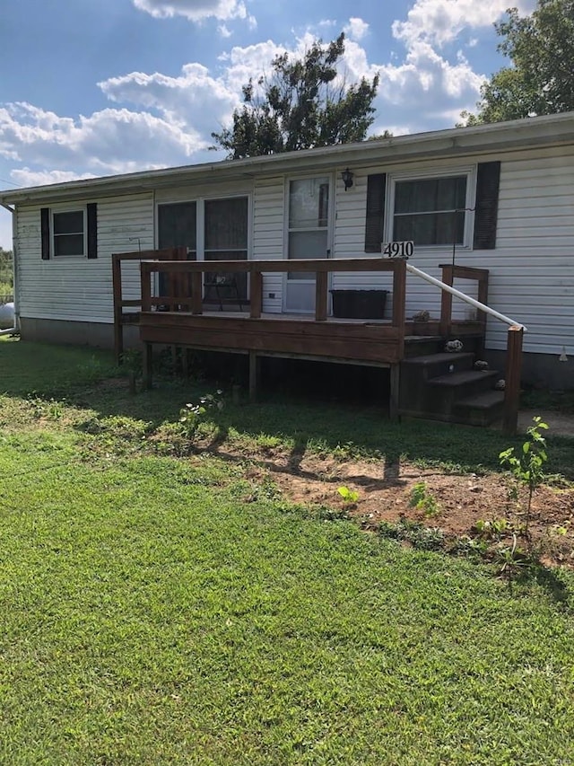 back of house with a wooden deck and a lawn