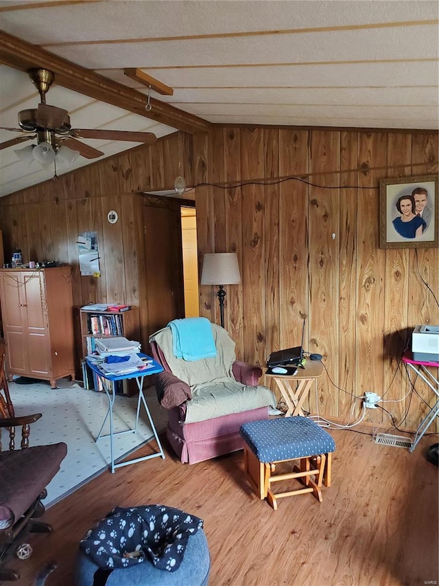 living area with vaulted ceiling with beams, wooden walls, ceiling fan, and wood-type flooring