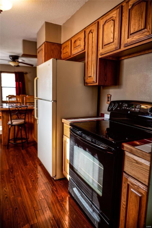 kitchen with dark hardwood / wood-style flooring, a textured ceiling, black range with electric stovetop, and ceiling fan