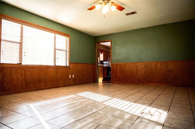 spare room featuring ceiling fan, plenty of natural light, and light tile patterned floors