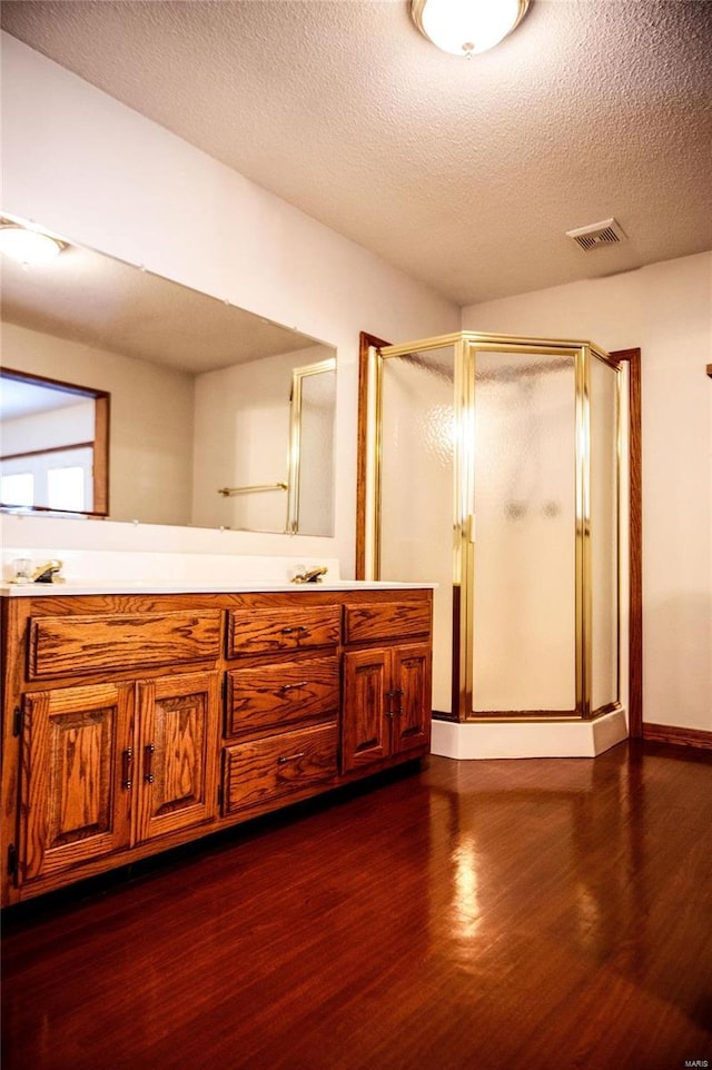 bathroom featuring vanity, a shower with shower door, a textured ceiling, and hardwood / wood-style flooring