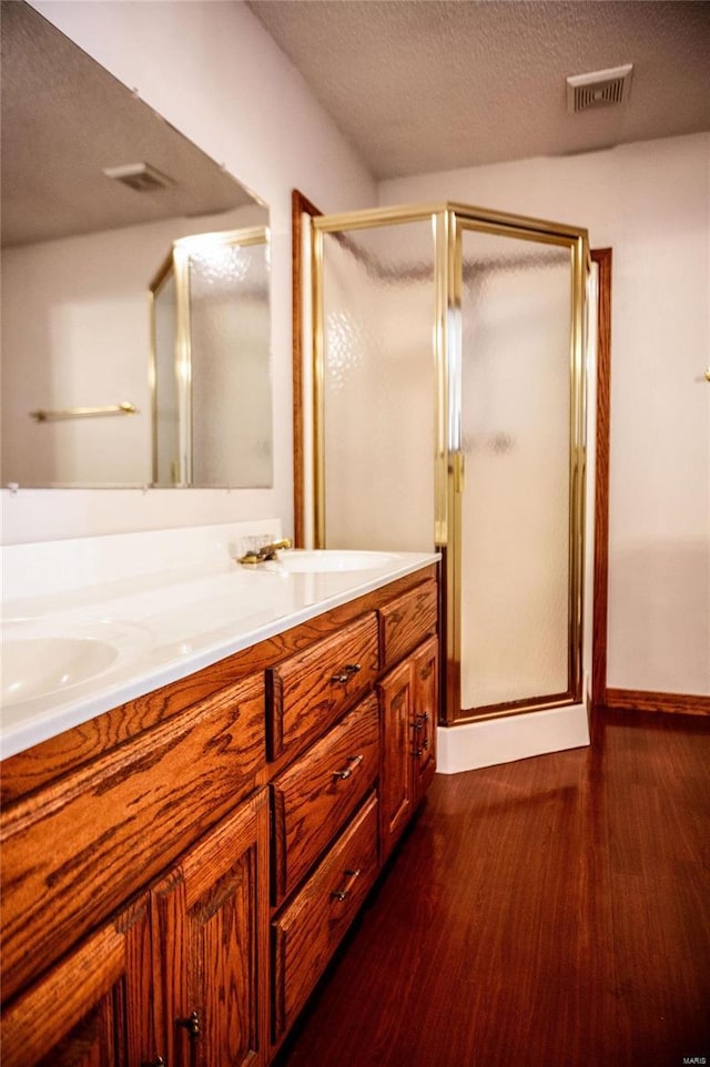 bathroom with vanity, a textured ceiling, hardwood / wood-style flooring, and a shower with shower door