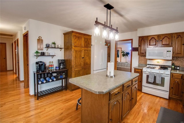 kitchen with a center island, light hardwood / wood-style flooring, backsplash, pendant lighting, and white appliances