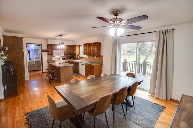 dining space featuring sink, ceiling fan with notable chandelier, and light hardwood / wood-style flooring