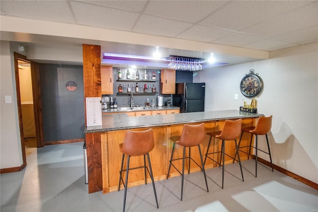 bar with a drop ceiling, black refrigerator, and sink