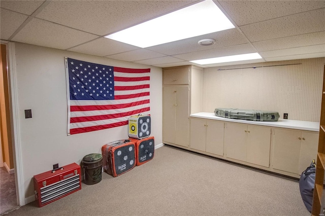 interior space featuring a paneled ceiling and light colored carpet