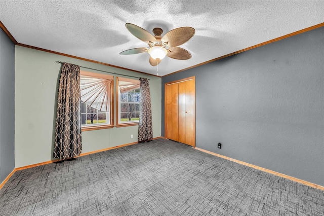 unfurnished bedroom with crown molding, ceiling fan, a textured ceiling, carpet floors, and a closet