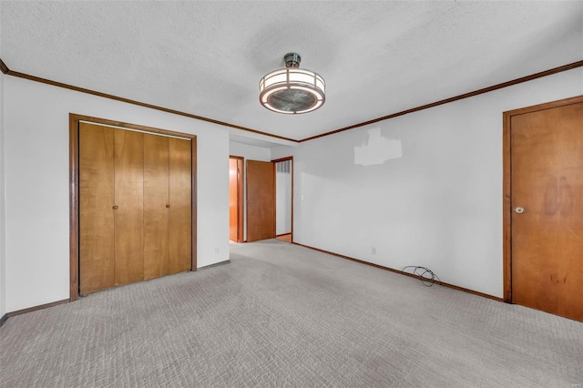 unfurnished bedroom featuring light carpet, a textured ceiling, a closet, and crown molding