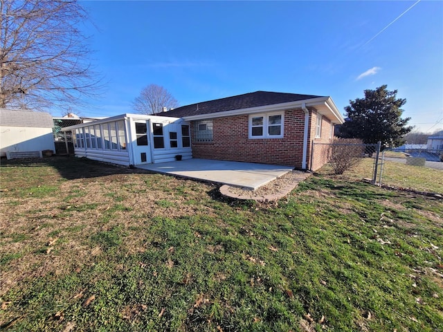 rear view of property with a lawn, a sunroom, and a patio