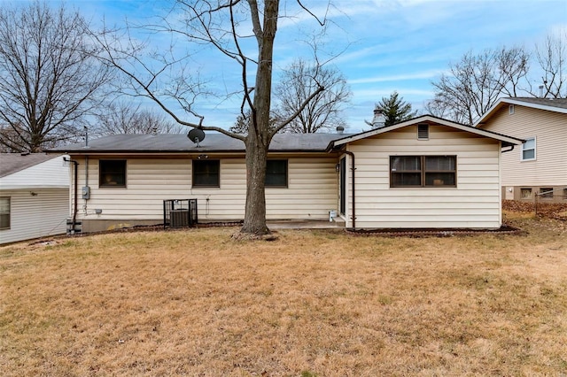 back of property with central AC unit and a yard