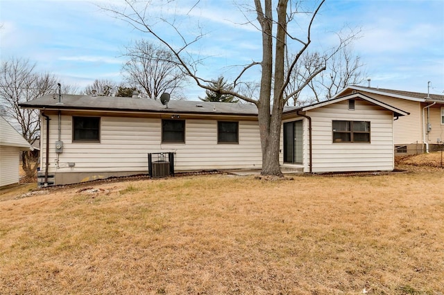 back of house with central air condition unit and a yard