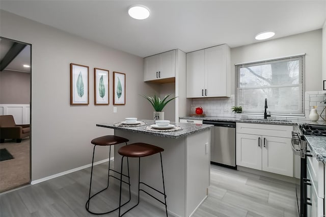 kitchen featuring a center island, white cabinets, sink, decorative backsplash, and appliances with stainless steel finishes