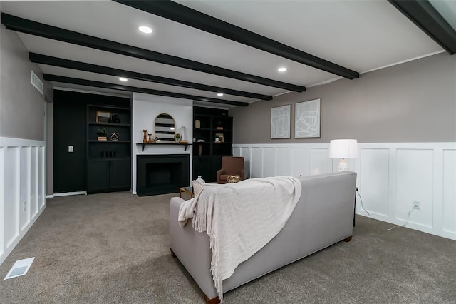 carpeted living room with beamed ceiling and built in shelves