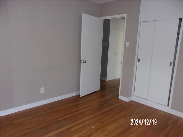 unfurnished bedroom featuring wood finished floors, a closet, and baseboards