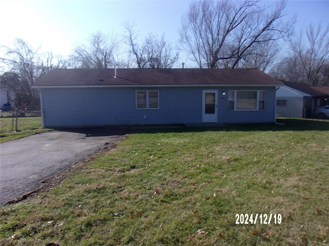 view of front of property with aphalt driveway, fence, and a front yard