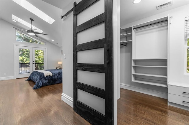 bedroom with access to exterior, visible vents, lofted ceiling with skylight, a barn door, and wood finished floors