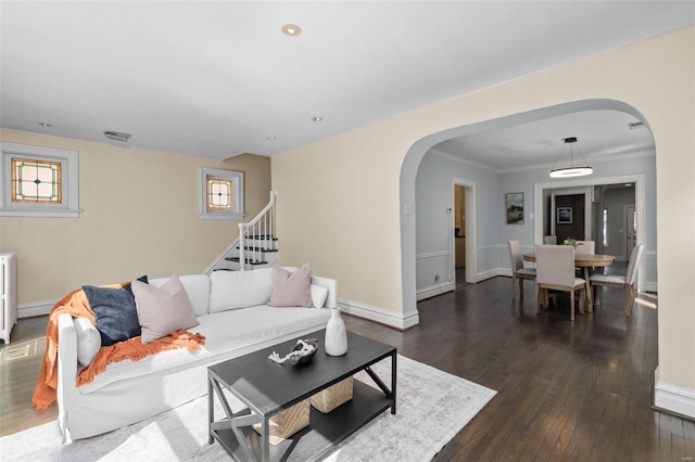 living area featuring dark wood-style floors, stairway, arched walkways, radiator, and baseboards