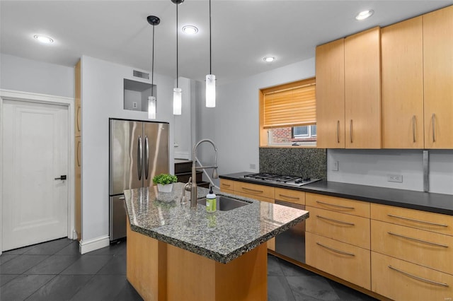 kitchen featuring visible vents, dark tile patterned floors, a center island with sink, a sink, and stainless steel appliances