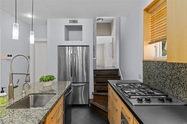 kitchen featuring visible vents, dark tile patterned flooring, a sink, appliances with stainless steel finishes, and tasteful backsplash