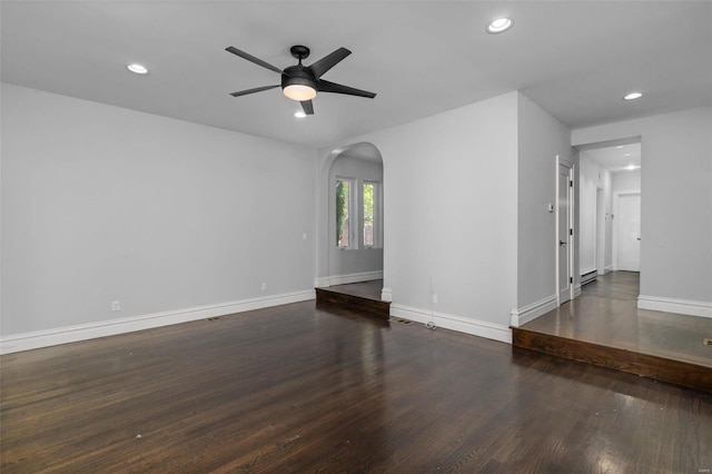 empty room with wood finished floors, baseboards, recessed lighting, arched walkways, and ceiling fan