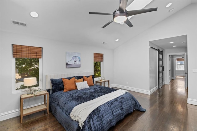 bedroom featuring wood finished floors, baseboards, visible vents, vaulted ceiling, and a barn door