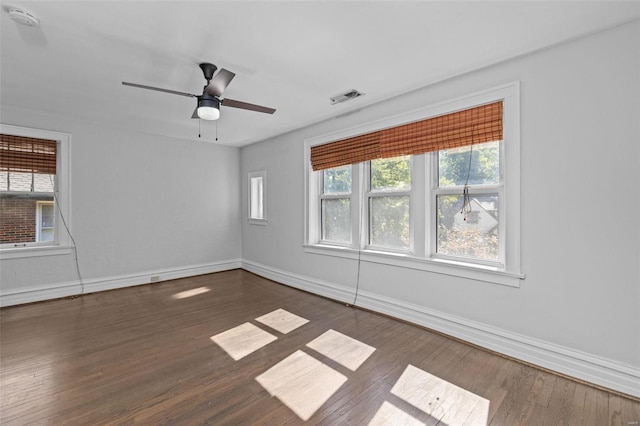 empty room featuring visible vents, baseboards, ceiling fan, and dark wood-style flooring