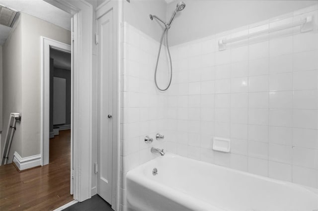 bathroom featuring visible vents, wood finished floors, tub / shower combination, and baseboards