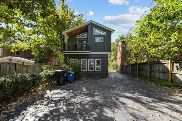 back of property featuring a balcony and fence