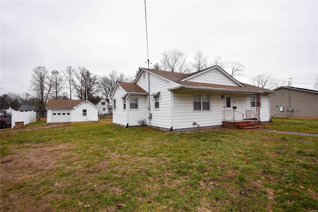 view of front of property featuring a garage, a front lawn, and an outdoor structure