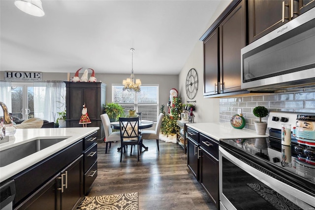 kitchen with sink, appliances with stainless steel finishes, hanging light fixtures, dark brown cabinets, and decorative backsplash