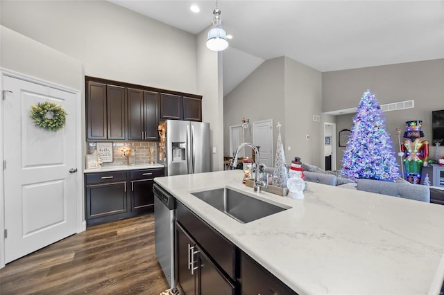 kitchen featuring lofted ceiling, sink, decorative light fixtures, stainless steel appliances, and backsplash