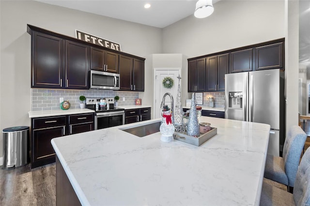 kitchen featuring sink, stainless steel appliances, and an island with sink