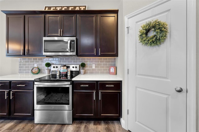 kitchen featuring appliances with stainless steel finishes, dark wood-type flooring, backsplash, and dark brown cabinetry