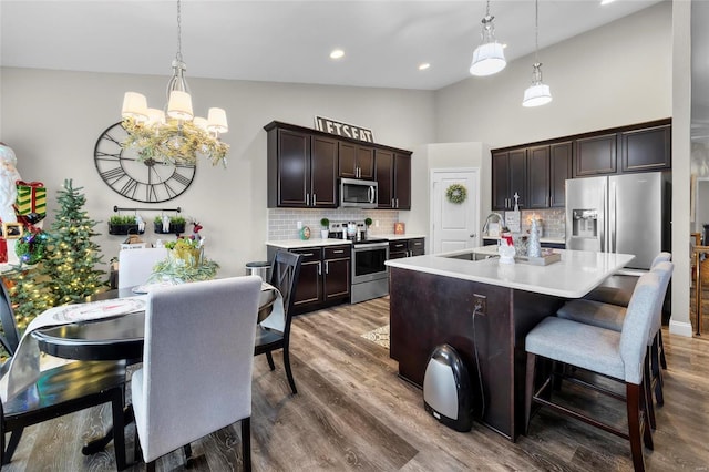 kitchen featuring sink, decorative light fixtures, appliances with stainless steel finishes, an island with sink, and backsplash