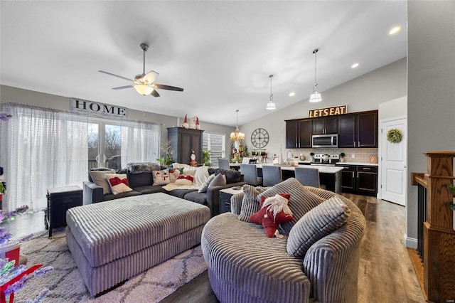 living room featuring dark wood-type flooring, ceiling fan with notable chandelier, and vaulted ceiling