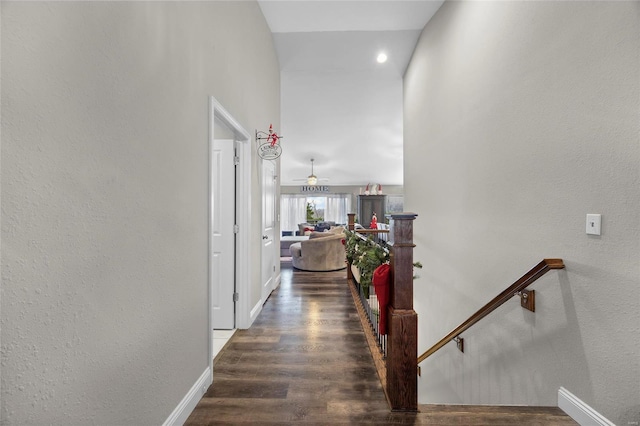 corridor featuring a towering ceiling and dark wood-type flooring