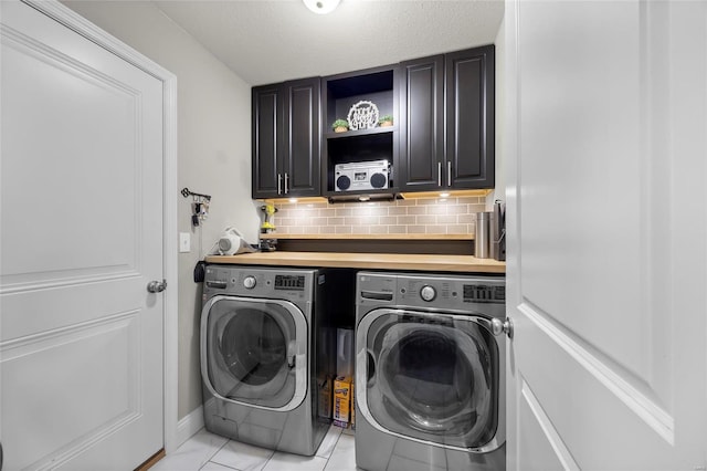 clothes washing area with light tile patterned flooring, cabinets, washer and clothes dryer, and a textured ceiling