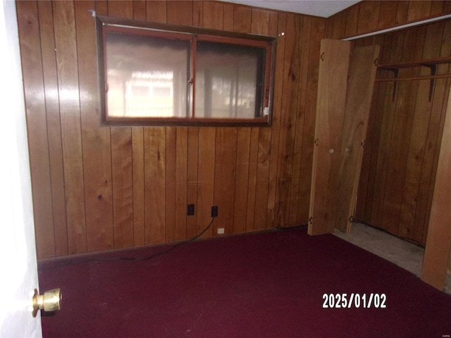 spare room featuring wooden walls and carpet