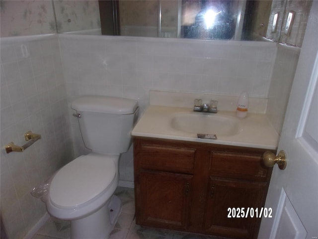 bathroom with vanity, tile walls, and toilet