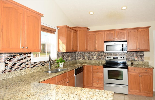 kitchen featuring decorative backsplash, stainless steel appliances, light stone counters, and sink