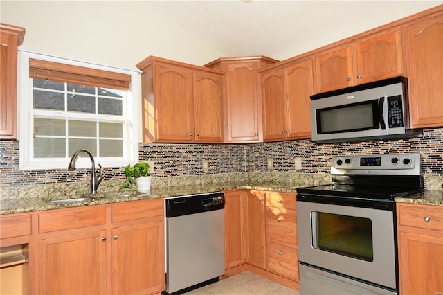 kitchen featuring light stone countertops, appliances with stainless steel finishes, backsplash, and sink