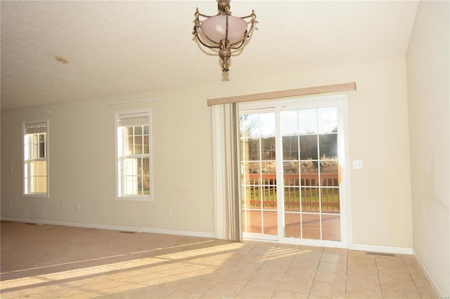 spare room featuring light tile patterned floors and an inviting chandelier