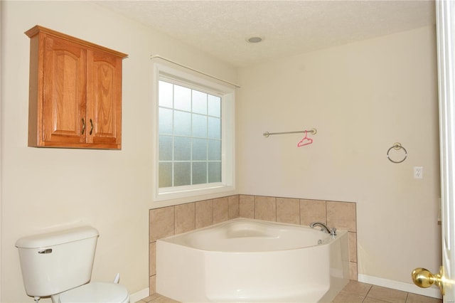 bathroom with a bathing tub, tile patterned flooring, a textured ceiling, and toilet