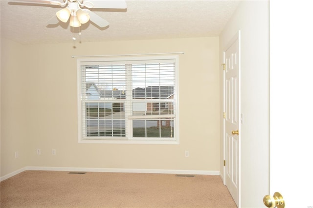 empty room featuring ceiling fan, light colored carpet, and a textured ceiling