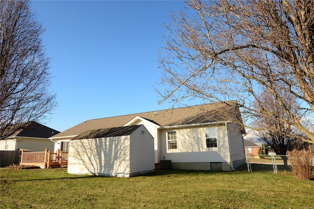 back of property with a yard, a wooden deck, and central AC